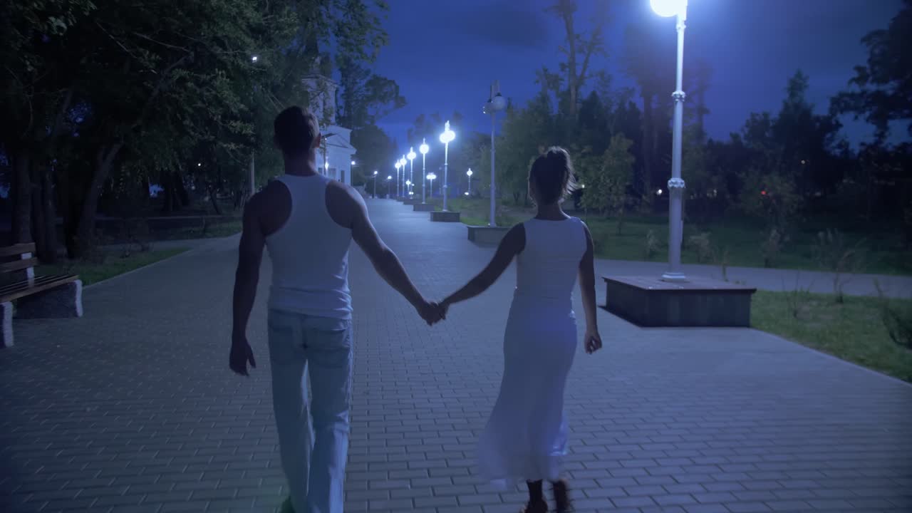 Couple Walking Hand-in-Hand at Night in Park