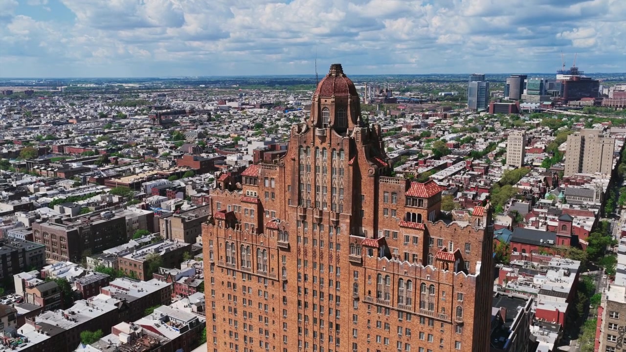 Vista aerea con drone dell'Hotel Divine Lorraine di Philadelphia che si erge sopra un vasto paesaggio urbano residenziale sotto un cielo blu drammatico con nuvole bianche gonfie.