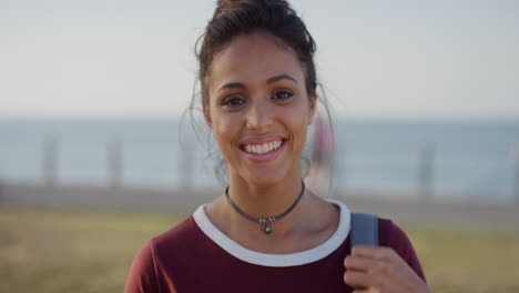 portrait attractive young hispanic woman running hand through hair smiling enjoying successful vacation lifestyle wind blowing on sunny seaside