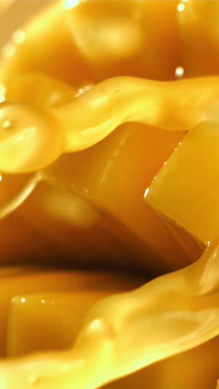 Miele dorato che cola su cubetti di mango appena tagliati