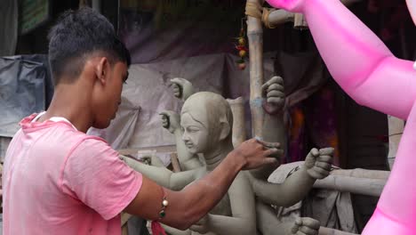 young indian artisan sculpting a clay statue of hindu goddess durga