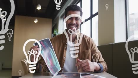 animation of lightbulb icons over mixed race businessman holding photo