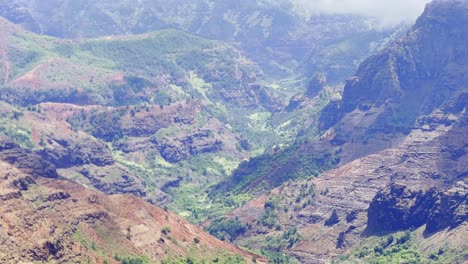 Cinematic-long-lens-booming-up-shot-of-colorful-Waimea-Canyon-covered-by-thick-clouds-on-the-Hawaiian-island-of-Kaua'i