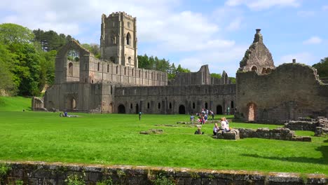 an abandoned cathedral abbey of fountains with people having picnics foreground