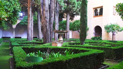 static shot of beautiful green garden with fountain in center, alhambra de granada, spain