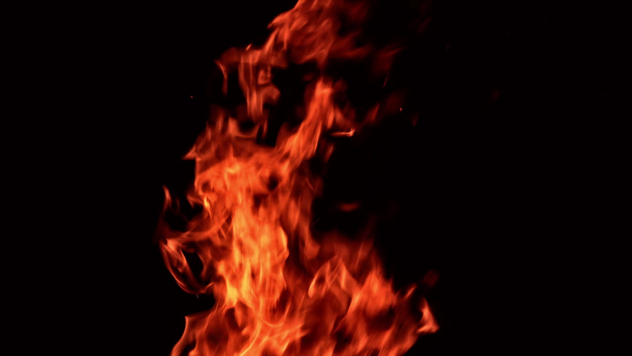 Flames of fire moving quickly to different sides in darkness. Tongues of fire fly up. Close up.