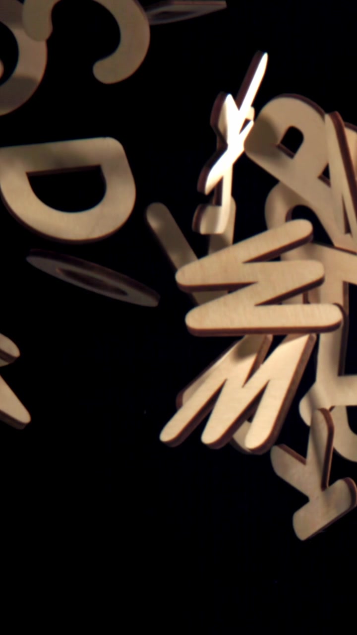 Wooden Alphabet Letters Falling in Slow Motion on Black Background