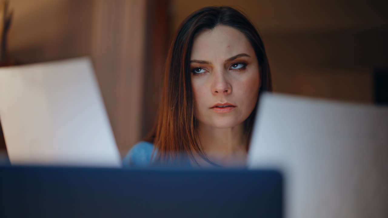 Worried employee reviewing papers at evening workplace closeup. Depressed woman