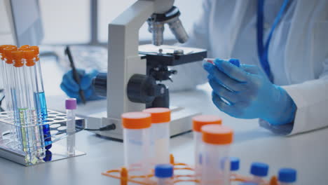 primer plano de un trabajador de laboratorio que realiza investigaciones utilizando un microscopio con una muestra de sangre etiquetada como tipo a