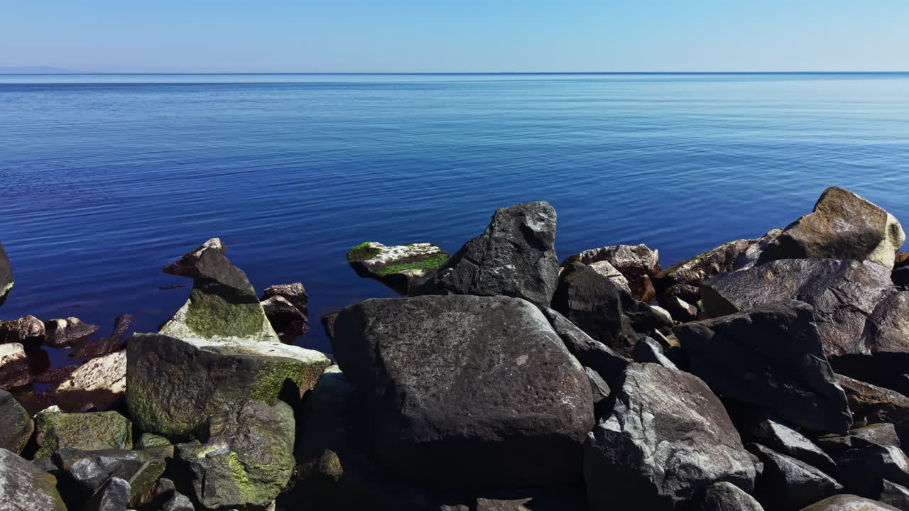 Udsigt over roligt vand ved den klippefyldte kyst på en klar dag uden skyer, der viser den fredfyldte natur ved et kystområde