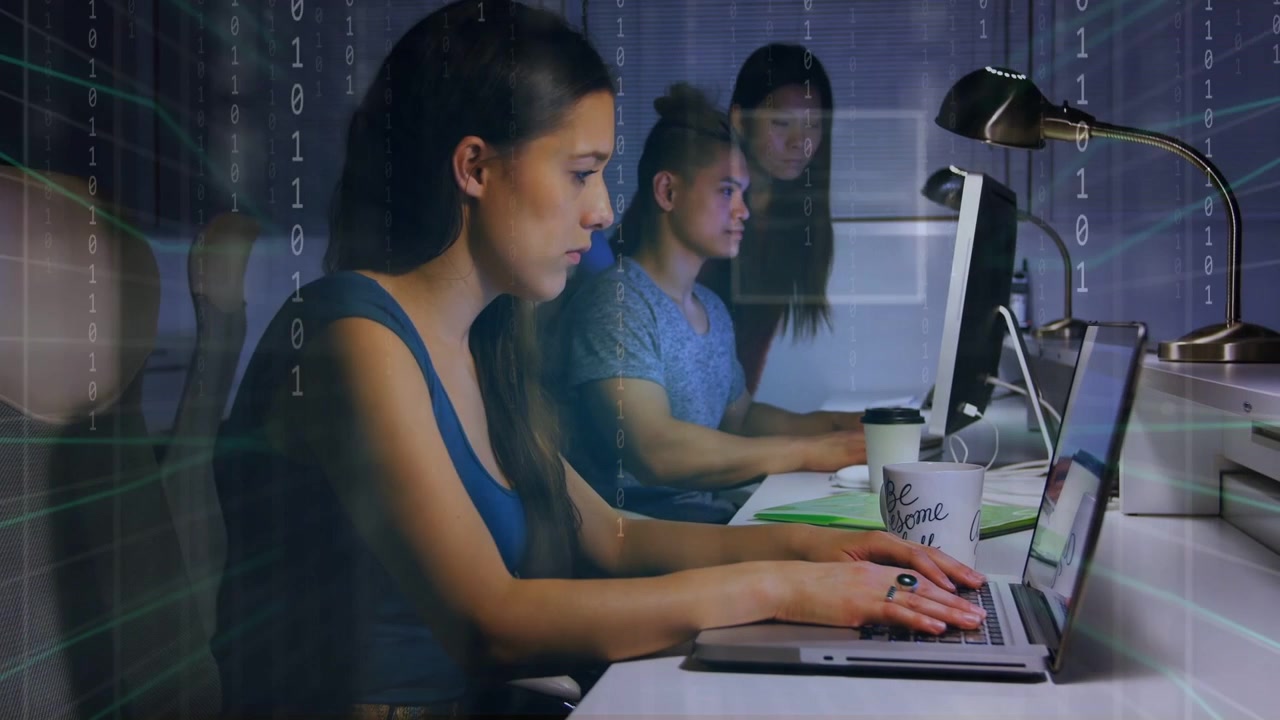 Front woman typing while team watching monitors, binary overlay rising as typing, aiding tech work