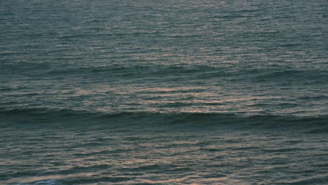 gentle sea waves with golden hour orange sunlight on surface. calming meditative nature ocean footage. prores 4k.