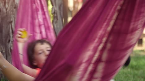 joven niña feliz en el campamento de verano acostada en hamacas coloridas relajándose jugando afuera con muñecas de peluche panda en el campo de hierba verde niños niños en cámara lenta