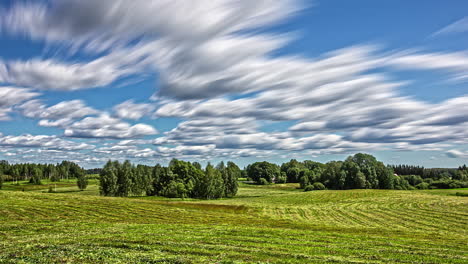 white fluffy clouds flow above green rural landscape on sunny day, fusion time lapse