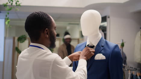 man arranges necktie on mannequin blazer