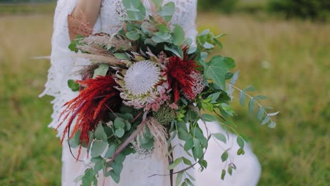 bride holding wedding bouquet. bride in dress standing on mountain and holding a bouquet