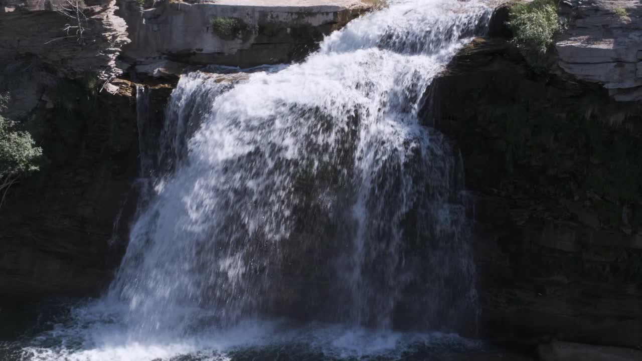 estratos de roca visibles como pequeñas cascadas de agua blanca sobre el acantilado