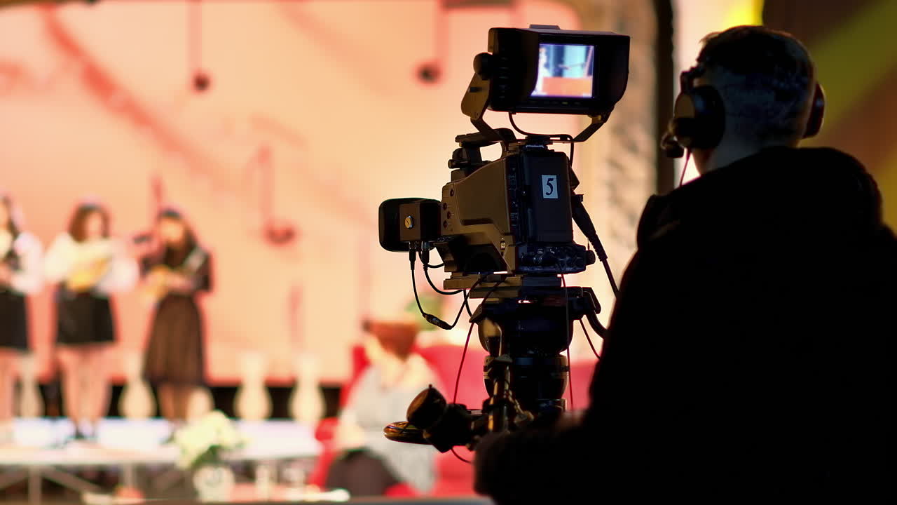 Man filming with professional camera on the backstage of a TV set