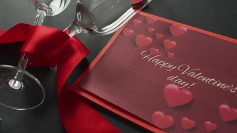 happy valentine's day text over champagne glasses with hearts and red ribbon