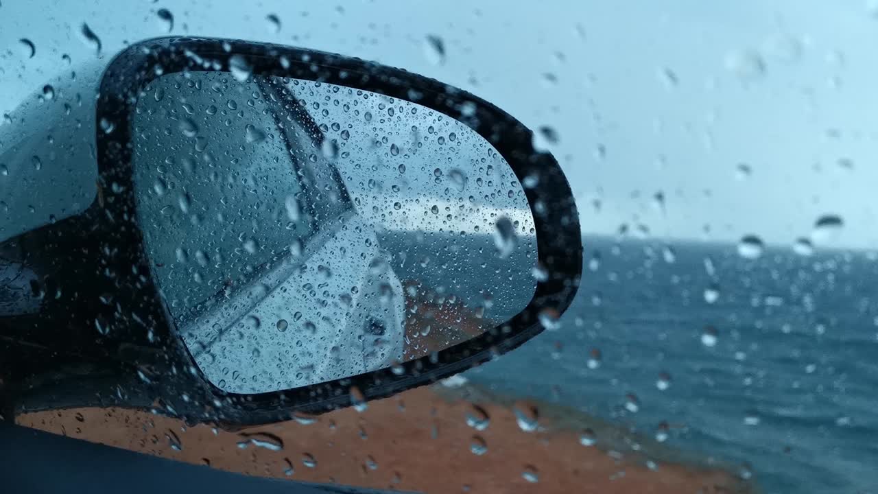 비방울이 차의 유리창과 거울 아래로 떨어집니다.