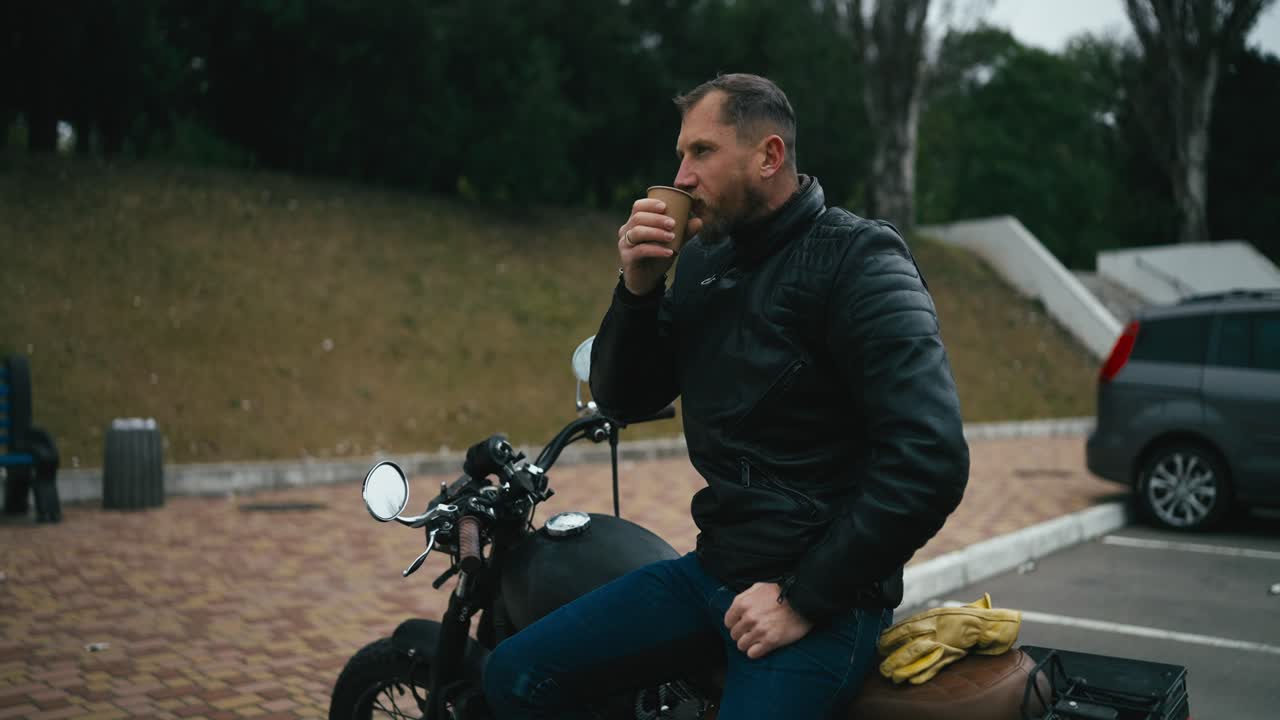 남자가 오토바이에서 커피를 마시고 있다
