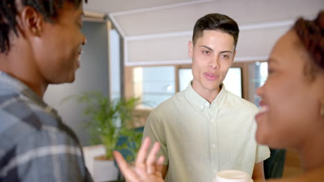 colleagues discussing work, holding coffee cups, engaging in conversation in office