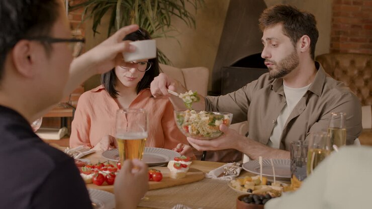 Niño sirviendo ensalada a un amigo en una cena