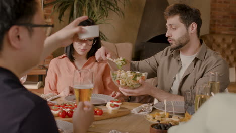 young boy serving salad to a friend at a dinner party