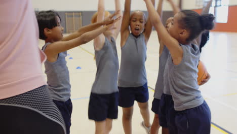 In school gym, children in sportswear cheering together in circle