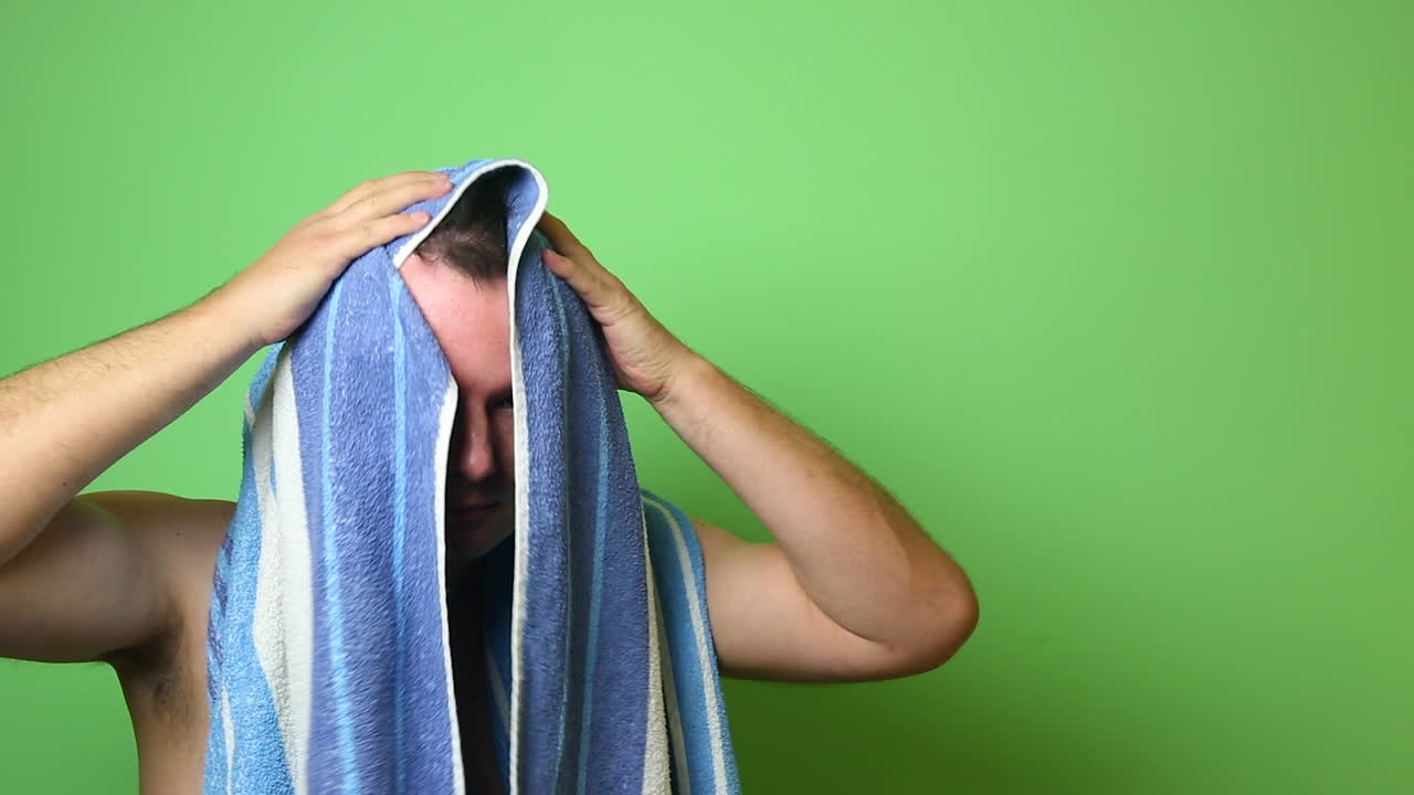 hombre limpiando el cabello con una toalla después del baño en pantalla verde