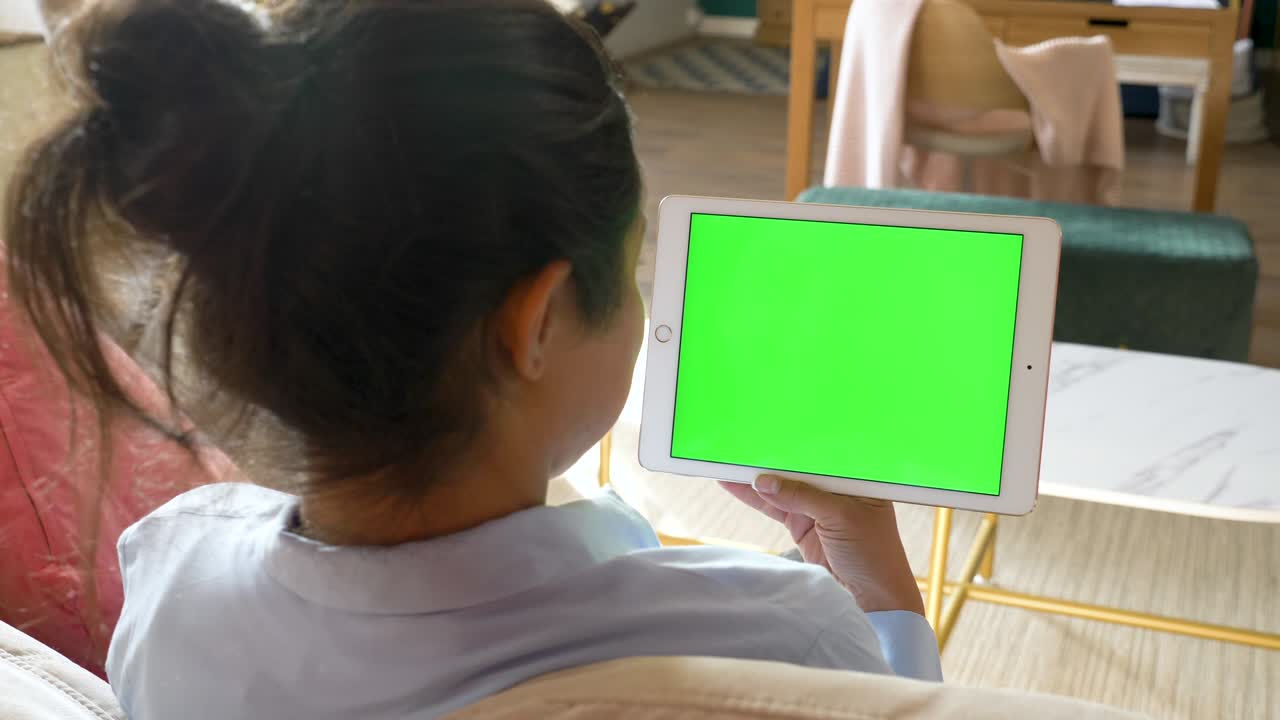 A Young Indian Woman Holds in Her hand Uses a Tablet with a Green Screen Chromakey Works Online in A Bright Room At Home