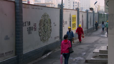 los trabajadores de una fábrica china caminan a casa por un callejón