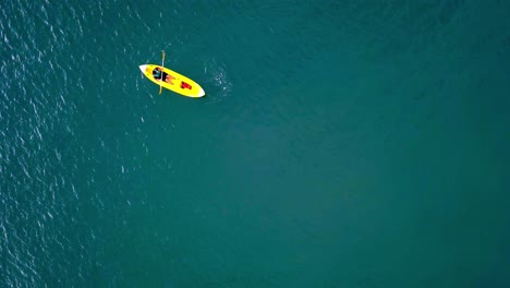 aerial top down shot of an unrecognizable man rowing on a kayak on turquoise color water