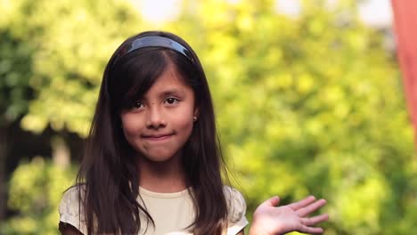 8-jähriges-Kleines-Mädchen-Sagt-Hallo-Mit-Ihrer-Hand-Auf-Grünem-Bokeh-Hintergrund