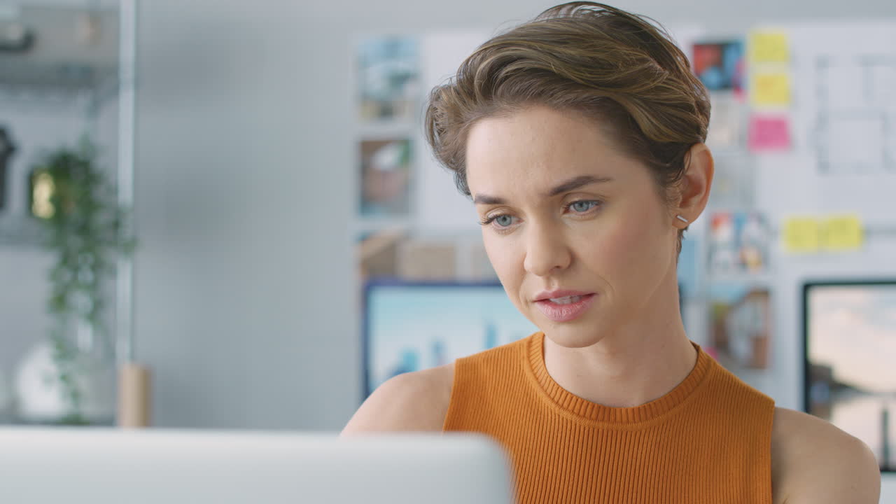 Nærbillede af smilende kvindelig arkitekt på kontor, der arbejder ved skrivebordet på sin bærbare computer.