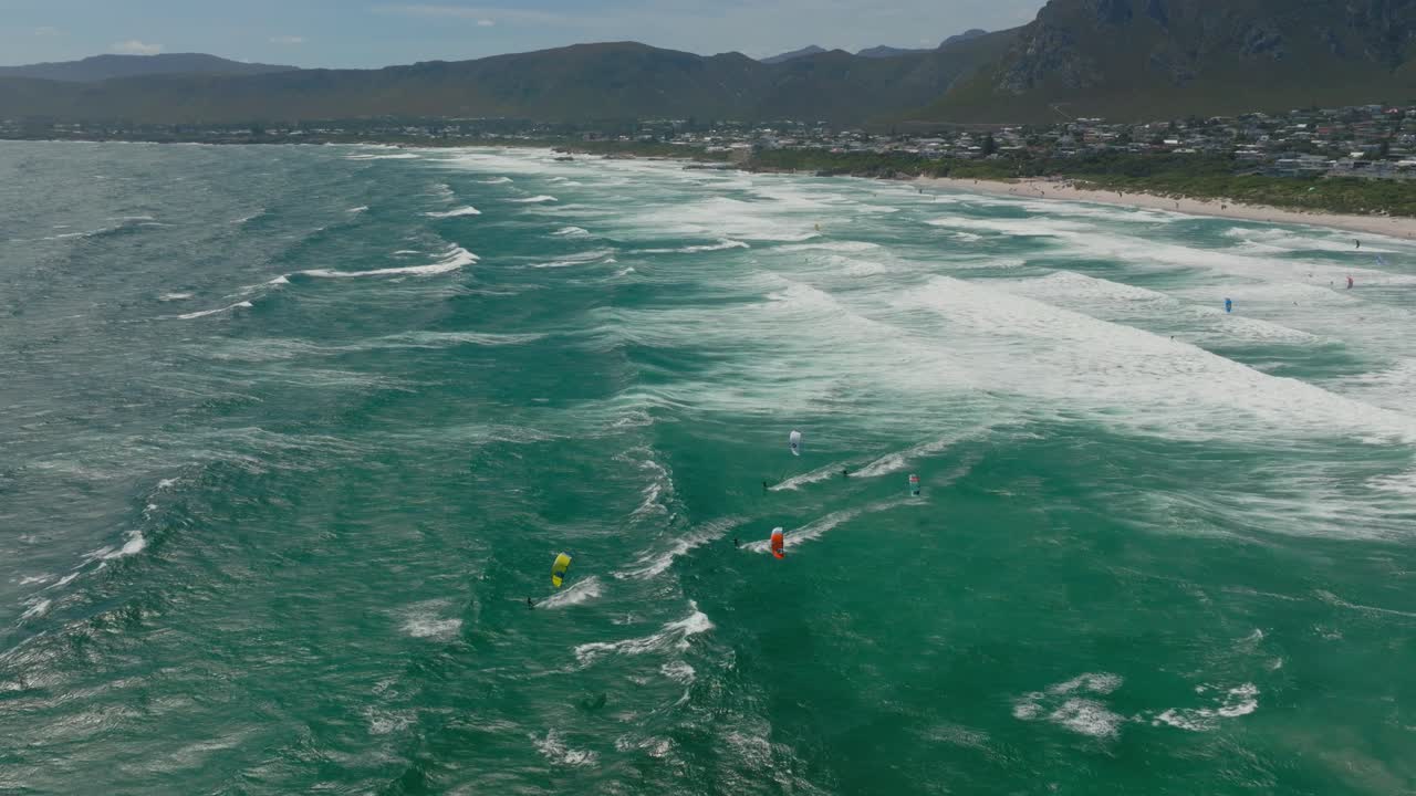 Kitesurfer rides waves off Hermanus beach in South Africa with ocean in side view