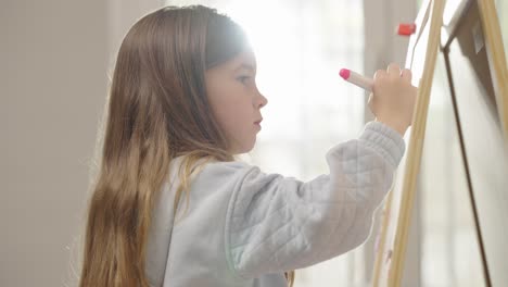 young girl drawing or writing on an easel