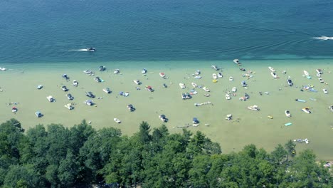 fotografía aérea de la orilla de barcos y personas en aguas poco profundas de lagos glaciares cristalinos en un soleado día de verano en el lago higgins de michigan
