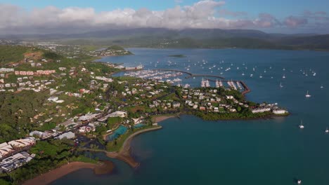 airle bay beach aerial drone coral sea marina pioneer bay port cannonvale heart of great barrier reef whitsundays islands whitehaven sunrise morning mist clouds jetty sailboats backward reveal motion