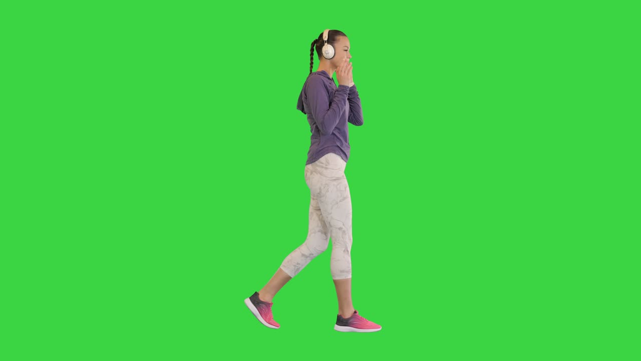 Young athletic girl on a walk with headphones on a Green Screen, Chroma Key
