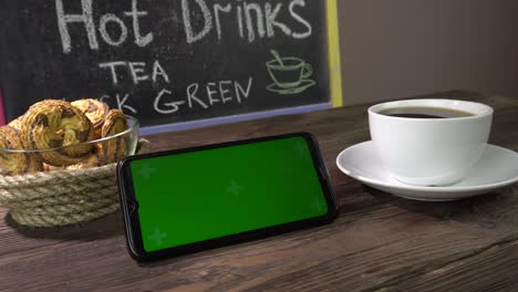 hot drink, cookies and smartphone on the table in the cafe.smartphone green screen.