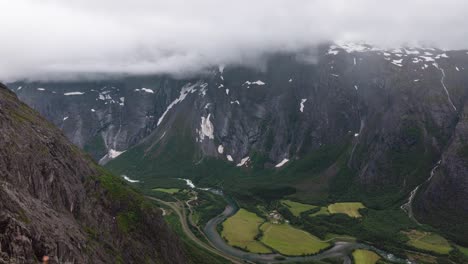 Time-Lapse-taken-from-a-high-point,-looking-down-towards-a-beautiful-valley-surrounded-by-tall-mountains-covered-with-snow