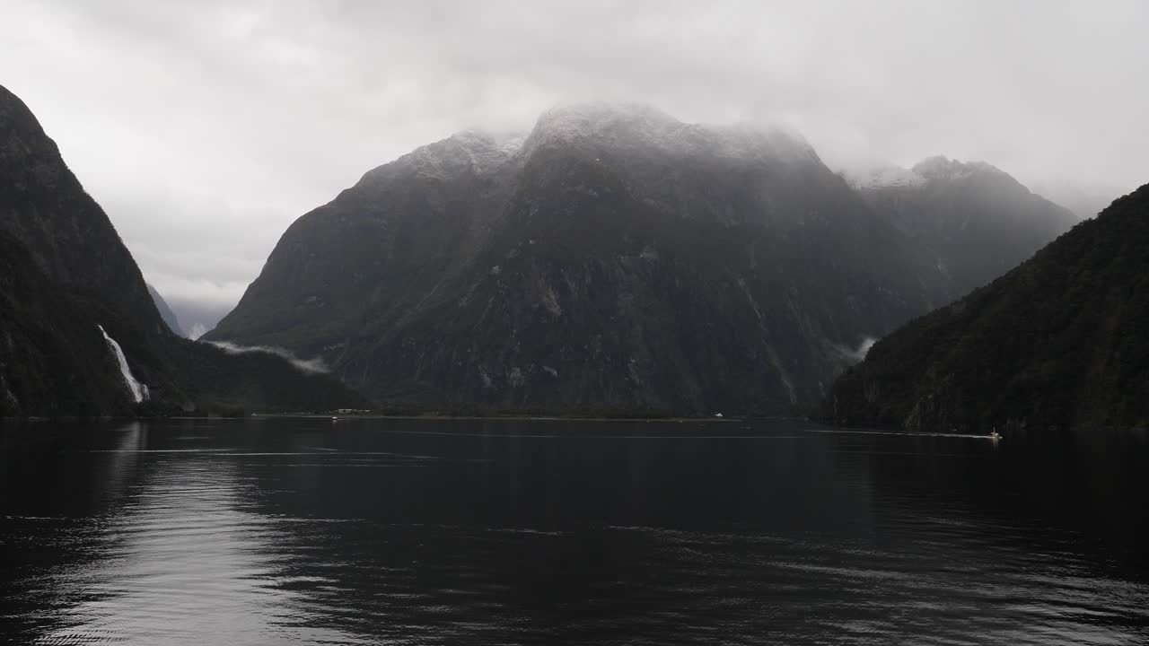 Small boat sailing at Milford Sound (Piopiotahi), Fiordland National Park on the South Island of New Zealand.Wide shot.