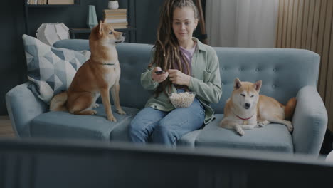 woman watching tv with dogs and popcorn