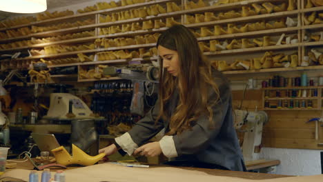 mujer artesana haciendo diseño de zapatos de patrón de cuero en taller de zapateros artesanales