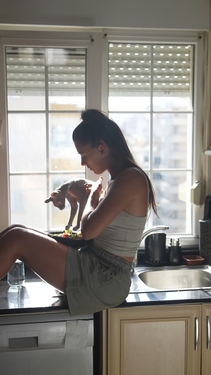 joven comiendo ensalada con su gato en la cocina