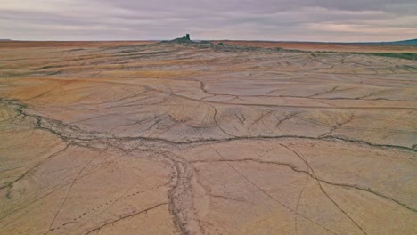 4k drone footage of utah’s factory butte badlands, with dramatic striated slopes, layered sedimentary rock formations, trails from offroading motor vehicles and the raw beauty of the desert landscape.