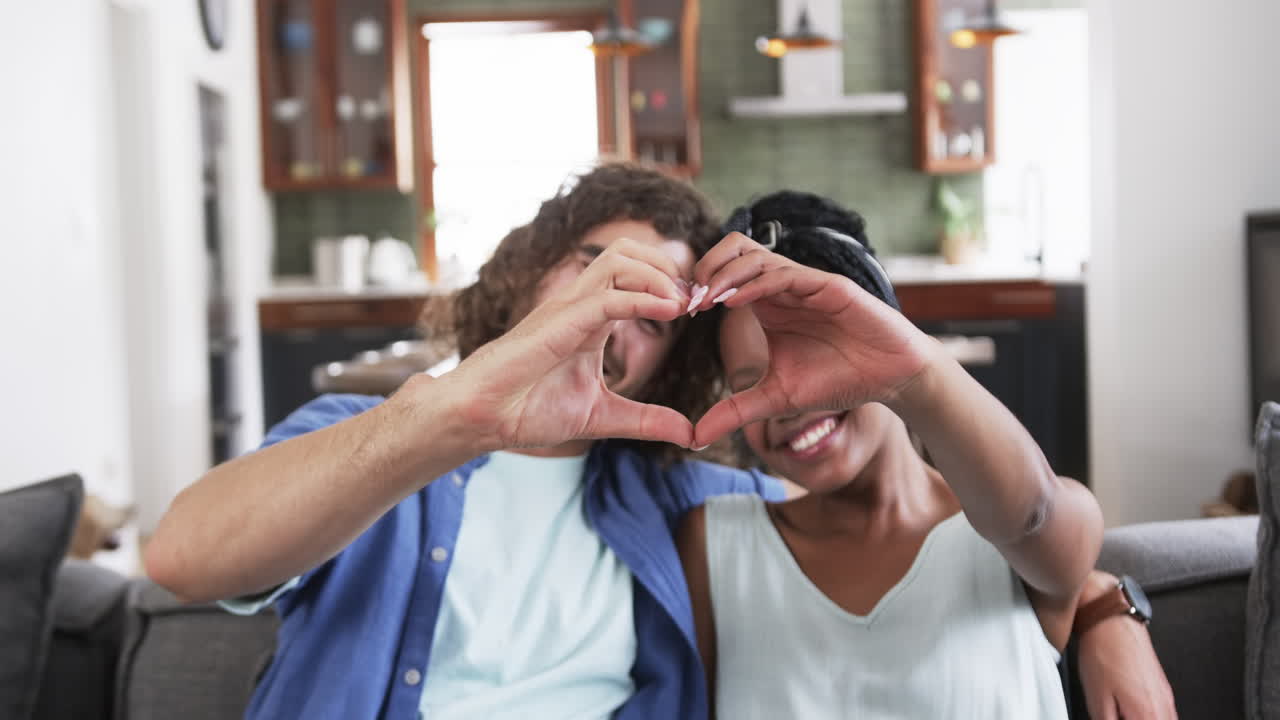 una pareja joven forma una forma de corazón con las manos en casa.