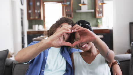 young couple forms a heart shape with hands at home