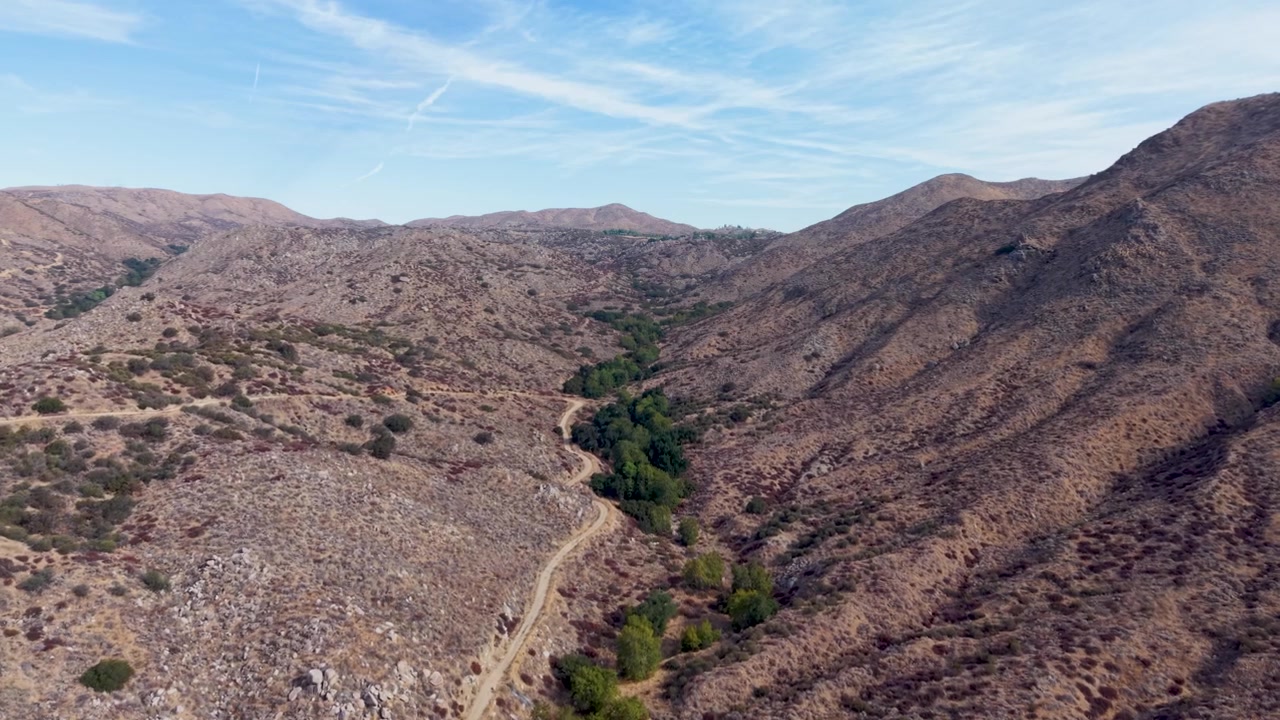 Montagne aride e aspre degli Stati Uniti occidentali viste attraverso gli occhi di una telecamera aerea. Sorvolando la calda e arida valle, vediamo sentieri e vegetazione dove si raccoglie l'acqua.